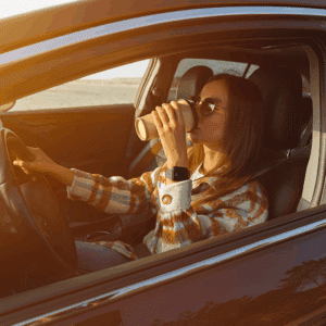 a woman drinking a coffee while driving