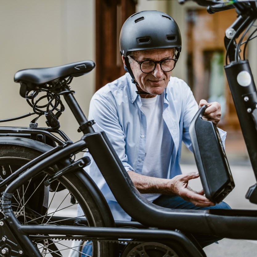 A man replacing and e-bike battery with a helmet on