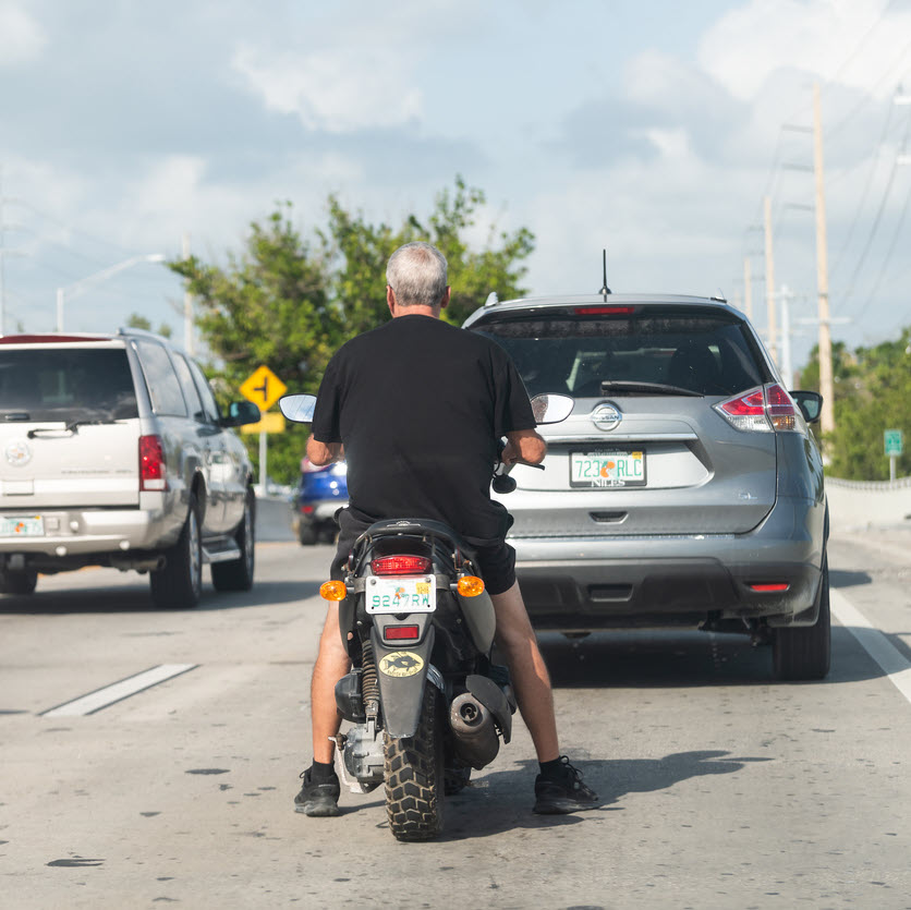Man riding a moped in traffic